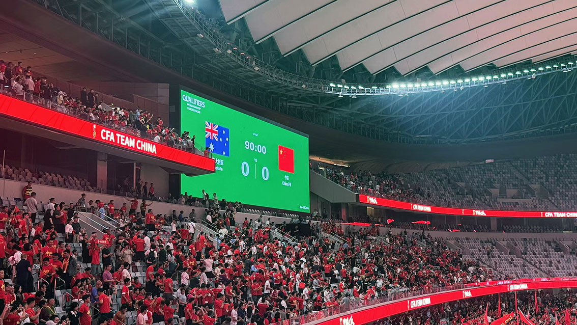QSTECH LED banner display running match content during a night game at Xi'an International Football Center
